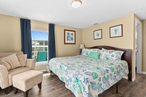 a bedroom with a bed and a chair and a window at Pier Watch in Flagler Beach
