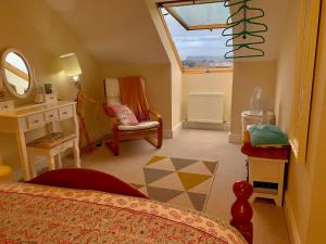 1 dormitorio con cama, espejo y silla en Loft Room @ Sean and Janes, en Ballycastle