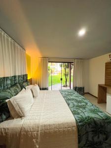 sypialnia z dużym łóżkiem i dużym oknem w obiekcie Pousada Praia dos Carneiros w mieście Praia dos Carneiros