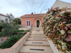 uma casa com um jardim com flores na parede em Chez Régine em Agde