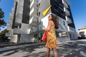 里米尼的住宿－Nero D'Avorio Aparthotel & SPA，站在建筑物前身穿衣服的女人