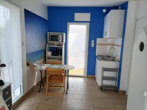 a kitchen with a table and a blue wall at Agréable studio indépendant proche mer in Saint-Hilaire-de-Riez