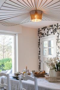 a dining room with a table and a chandelier at Villa Raphia - Maison d'hôtes in Hardelot-Plage