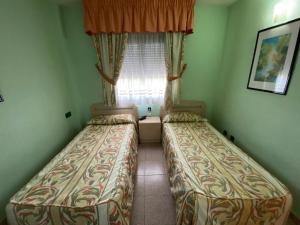 two beds in a small room with a window at APARTAMENTO CERCA DEL PASEO Y PORT AVENTURA in Salou