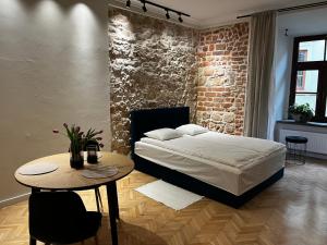 Apartamenty Rynek 5 في لوبلين: غرفة نوم بحائط من الطوب وسرير وطاولة