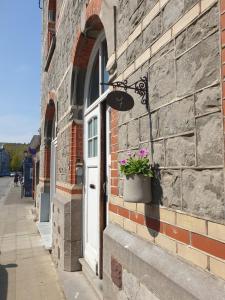 a brick building with a door with a potted plant on it at Escale Chambre d'hôtes Au coeur du vieux Profondeville entre Namur et Dinant in Profondeville