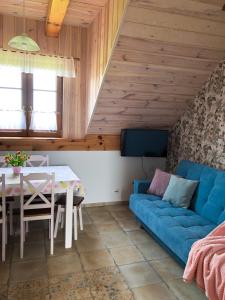 uma sala de estar com um sofá azul e uma mesa em WIEJSKI APARTAMENT W DOMU NAD JEZIOREM em Mikołajki
