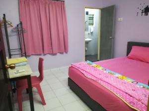 a bedroom with a pink bed and a table and a chair at 30 Guest House in Malacca