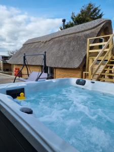 a hot tub with a thatch roof and a yellow duck in it at The Thatchie in Deal