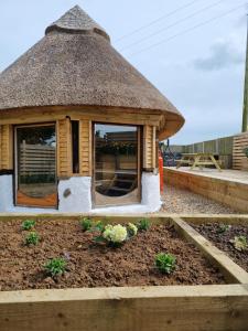 a small house with a thatched roof on a garden at The Thatchie in Deal