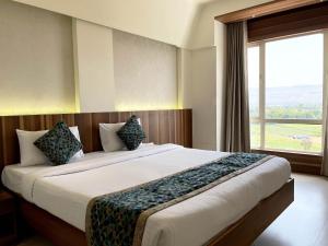a bedroom with a large bed with a large window at Hotel Grand Parivaar in Igatpuri