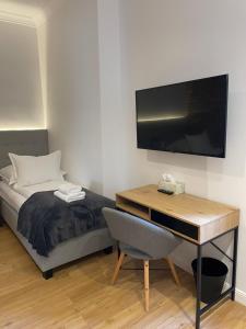 a bedroom with a bed and a desk with a television at New Sobieski Apartments by OneApartments in Sopot