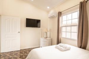 a bedroom with a bed and a tv on the wall at Mariner Suites in Christ Church