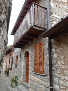 un edificio de piedra con balcón de madera. en Casa vacanze Casa di Corte, en Adrara San Rocco