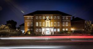 un grand bâtiment en briques avec des lumières devant lui dans l'établissement Kingsland Hotel, à Harrow