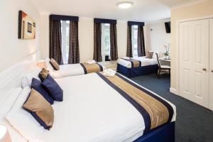 a hotel room with two beds and a desk at Kingsland Hotel in Harrow