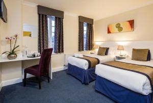 a hotel room with two beds and a desk at Kingsland Hotel in Harrow