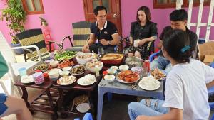 een groep mensen die rond een tafel zitten met eten bij Thuy Hang Motel in Long Hai
