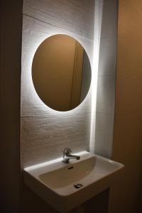 un lavandino da bagno con sopra uno specchio rotondo di Studio2 in Katerini a Kateríni