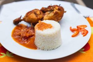 un plato blanco de comida con arroz y carne en Bénin Berge hotel, en Cotonou
