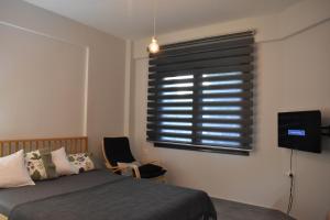 una camera da letto con un letto, una finestra e una sedia di Studio2 in Katerini a Kateríni