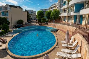 una piscina con sillas y una persona en el agua en Menada Sunset Kosharitsa Apartments, en Kosharitsa