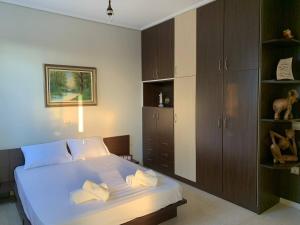1 dormitorio con cama blanca y armarios de madera en Villa Akti en Kalamata