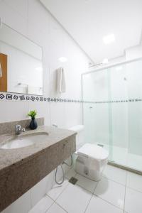 a bathroom with a toilet, sink, and shower at Hotel Olympia in Vila Velha