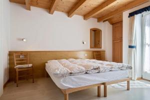 Cama en habitación con techo de madera en Cesa de Agnese en Canazei