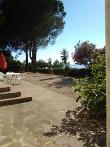 un patio con mesa, sillas y árboles en La casa sul tramonto - Capoliveri - services included, en Capoliveri