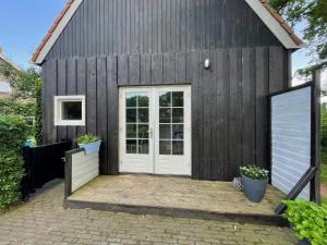 een kleine zwarte schuur met een witte deur bij B&B Woudzicht in Oudeschoot