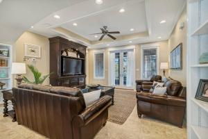 Il comprend un salon doté d'un mobilier en cuir et d'une télévision à écran plat. dans l'établissement Beach Club Cottage 23 - Luxurious Private Home!, à Gulf Shores