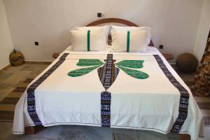 um quarto com uma cama com lençóis brancos e almofadas em Hotel Otsunami em Lomé