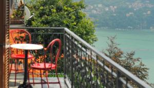 d'un balcon avec des chaises rouges, une table et une vue sur l'eau. dans l'établissement Como Lake Panorama Apartment Olivia, à Cernobbio