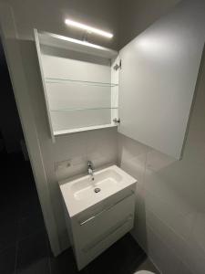 a white bathroom with a sink and a mirror at Studio Just For 2 in Ostend