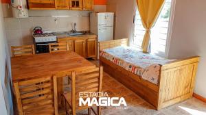 cocina con armarios de madera, mesa y cama en Cabañas en Cuadro Nacional en San Rafael