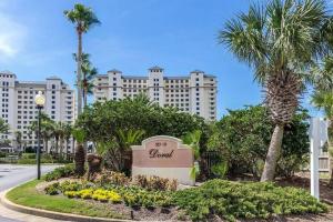 a sign in front of a large building with palm trees at The Beach Club Doral 306 - Spacious Beachfront Condo! in Gulf Shores