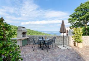 een patio met een tafel en stoelen en een parasol bij Apartments Marijana in Ičići