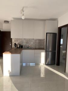 a kitchen with white cabinets and a stainless steel refrigerator at Appartement in Kallikratia in Nea Kallikrateia