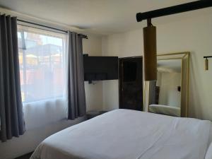 1 dormitorio con cama blanca y ventana grande en Hotel Naramu, en San Miguel de Allende