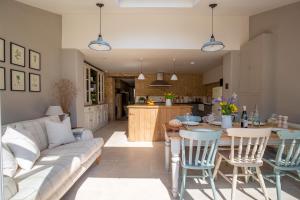 uma cozinha e sala de estar com um sofá e uma mesa em Gleneda Cottage - a renovated, traditional Cotswold cottage full of charm with fireplace and garden em Bourton on the Hill