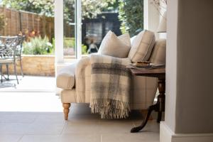 uma sala de estar com uma cadeira com um cobertor em Gleneda Cottage - a renovated, traditional Cotswold cottage full of charm with fireplace and garden em Bourton on the Hill