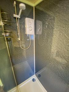 een badkamer met een douche met een douchekop bij The Cottar in Broadford