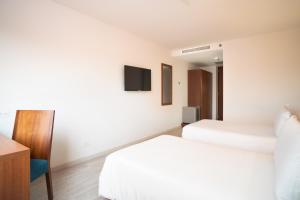 a hotel room with two beds and a tv at Hotel Habitel Select in Bogotá