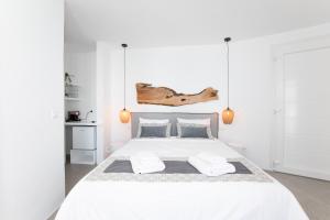 a white bedroom with a large white bed with two pillows at Mytheo in Mýkonos City