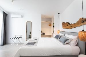 a white bedroom with a large white bed and a mirror at Mytheo in Mýkonos City
