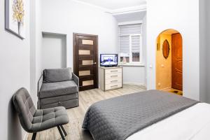 - une chambre avec un lit, une chaise et une télévision dans l'établissement Apartments Galitskaya street, à Lviv
