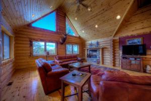 a living room with leather furniture in a log cabin at Black Diamond Lodge in Lead