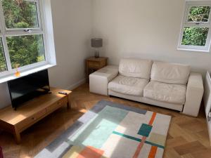 uma sala de estar com um sofá branco e uma televisão em Headingley Excellent 1 bedroom apartment em Leeds