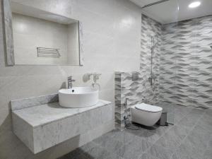 a white bathroom with a sink and a toilet at Imperial Suites Hotel in Manama